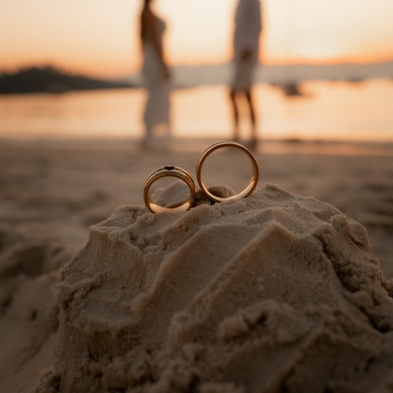 two wedding rings sitting in the sand on a beach